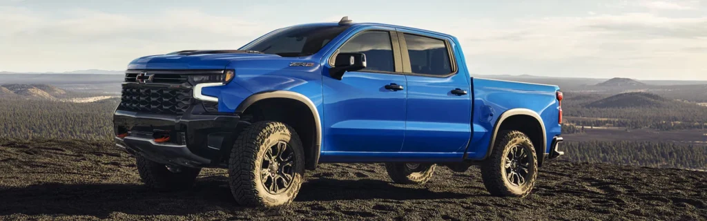 Blue Chevrolet Silverado 1500 ZR2 parked on rugged terrain overlooking a scenic landscape.